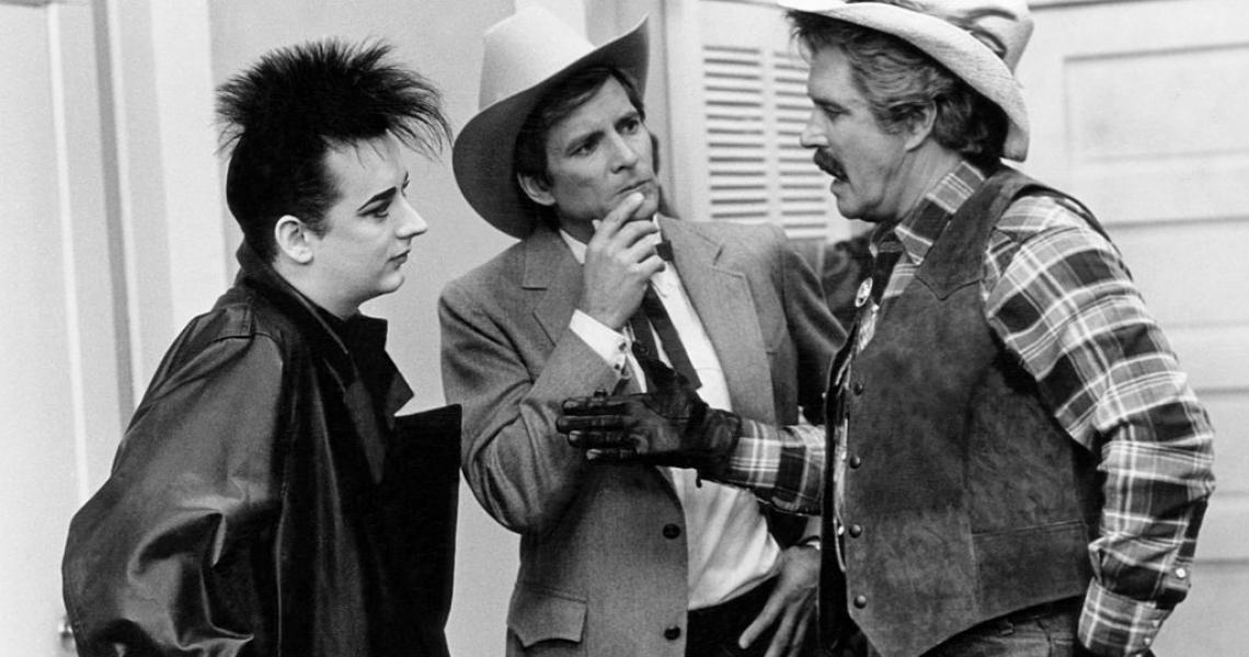 THE A-TEAM -- "Cowboy George" Episode 16 -- Pictured: (l-r) Boy George as Himself, Dirk Benedict as Templeton 'Faceman' Peck, L.Q. Jones as Chuck Danford (Photo by NBCU Photo Bank/NBCUniversal via Getty Images via Getty Images)